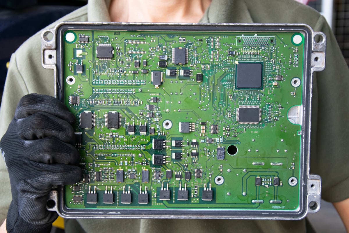 KFZ-Mechaniker hält ein ausgebautes Steuergerät (ECU) in der Hand – Steuergeräte Reparatur bei ONEREPEX Rosenheim