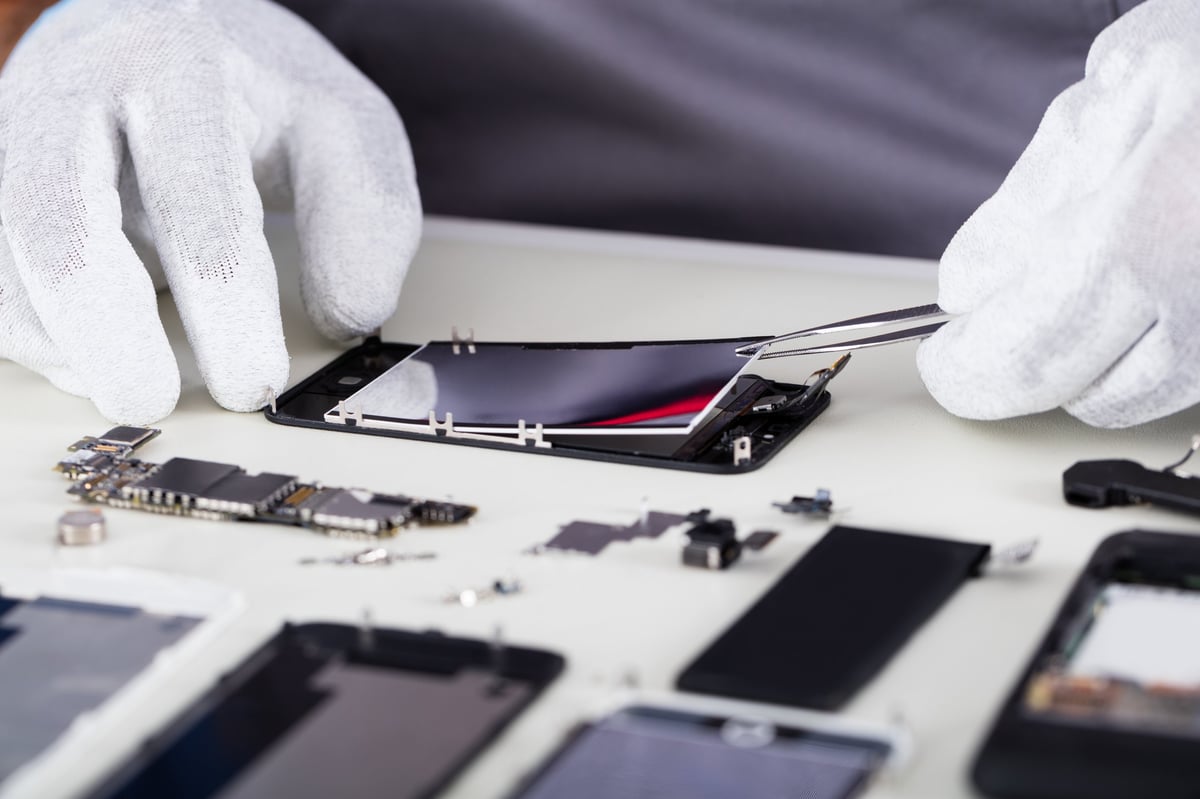 Techniker zerlegt ein Smartphone mit der Pinzette